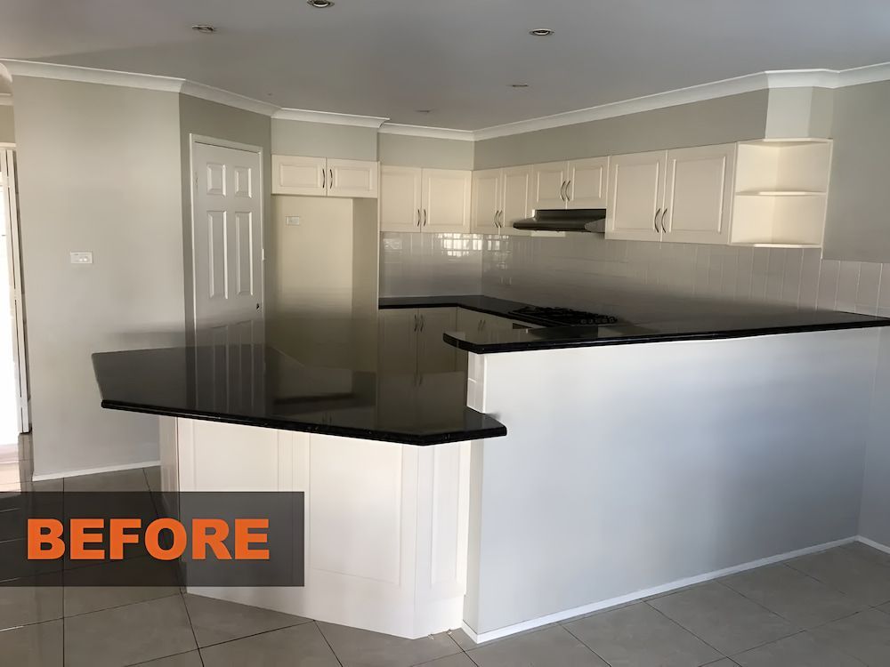 A Before Picture Of A Kitchen With White Cabinets And Black CounterTops — United Kitchens and Joinery in Oak Flats, NSW