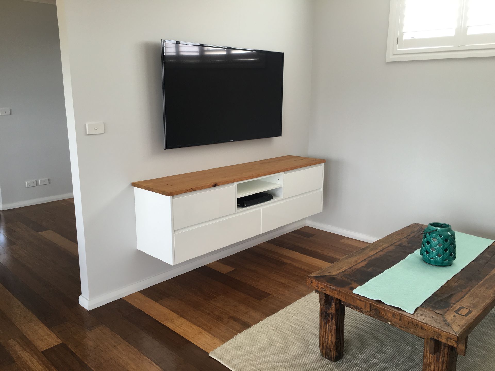 A Living Room With A Flat Screen Tv Mounted On The Wall — United Kitchens and Joinery in Oak Flats, NSW