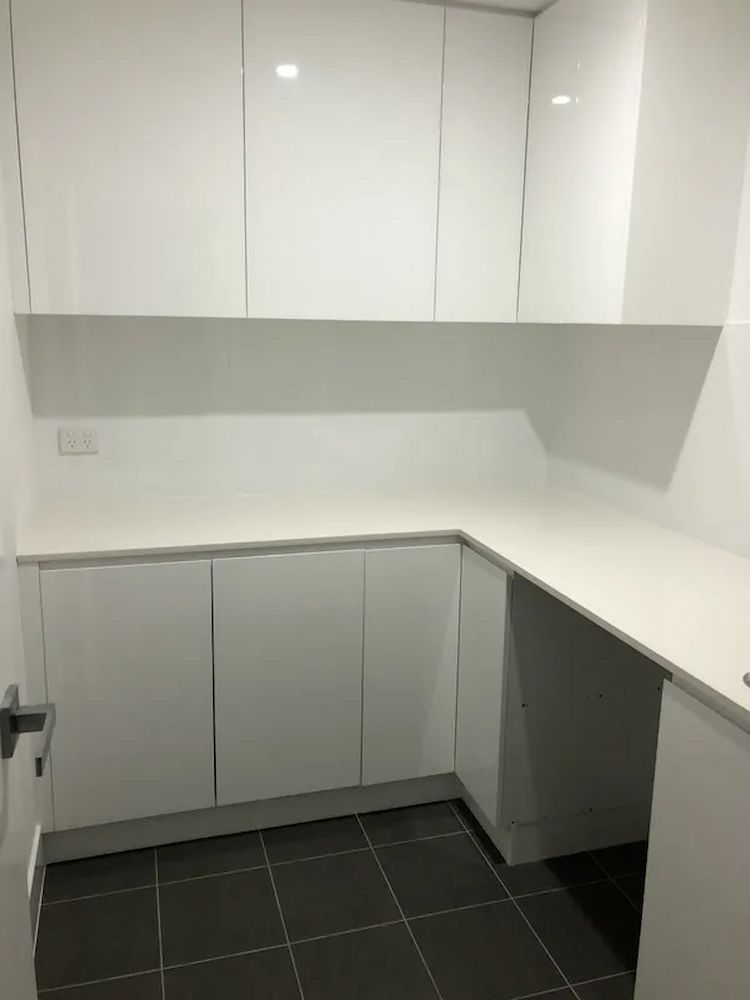 A Kitchen With White Cabinets And A Black Tile Floor — United Kitchens and Joinery in Oak Flats, NSW