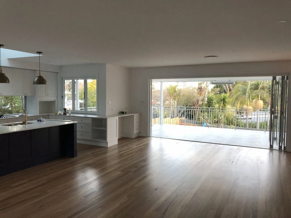 A Large Empty Room With Hardwood Floors And Sliding Glass Doors — United Kitchens and Joinery in Oak Flats, NSW