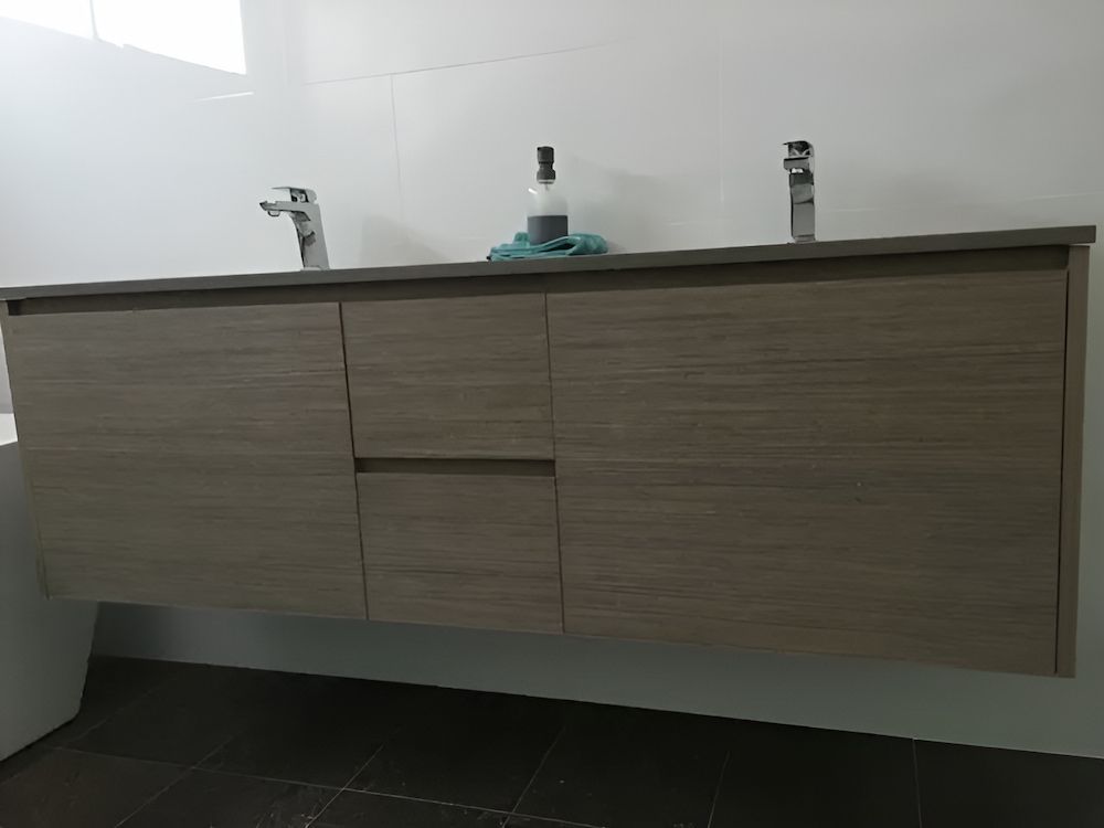 A Bathroom Vanity With Two Sinks And A Bottle Of Soap On Top Of It — United Kitchens and Joinery in Oak Flats, NSW