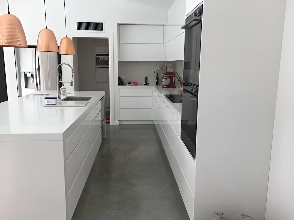 A Kitchen With White Cabinets And Copper Pendant Lights — United Kitchens and Joinery in Oak Flats, NSW