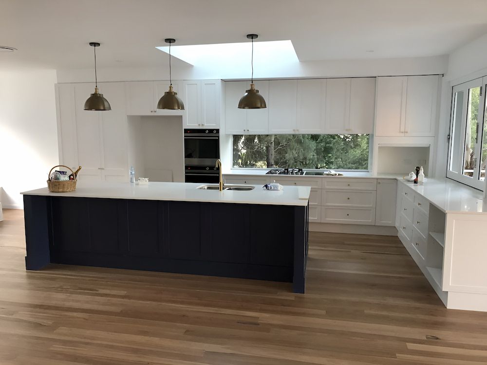 A Kitchen With White Cabinets And A Large Island In The Middle — United Kitchens and Joinery in Berry, NSW