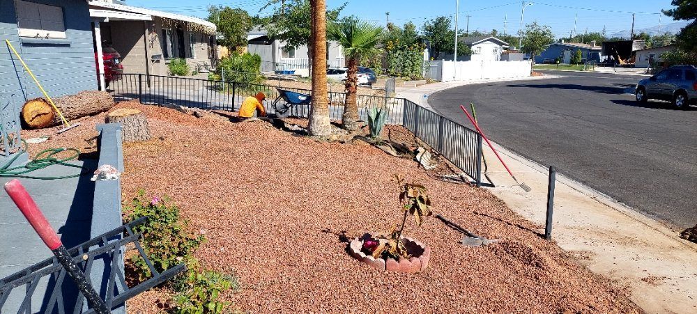 A fenced in yard with a few plants and a fire pit in the middle of it.