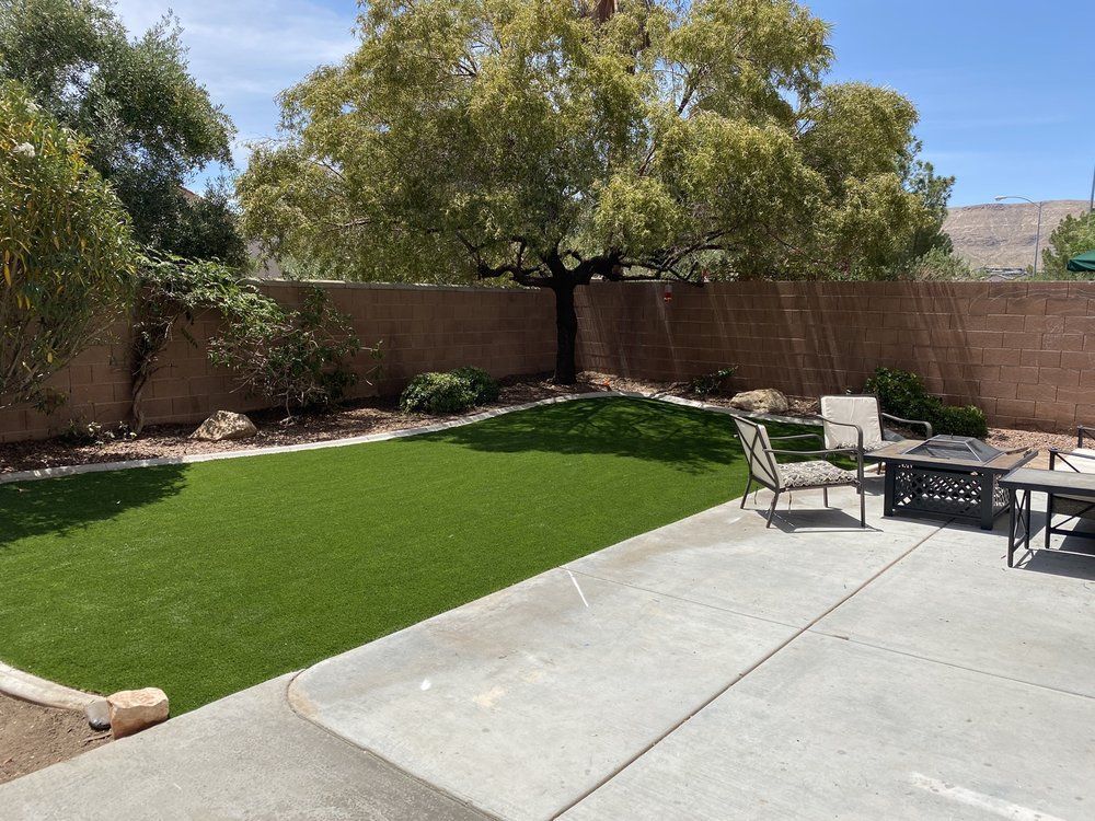 A patio with a table and chairs in a backyard.