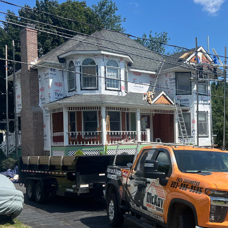 An orange truck is parked in front of a house under construction.