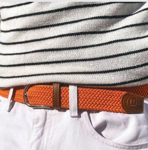 Orange woven belt worn with white pants and a striped sweater.