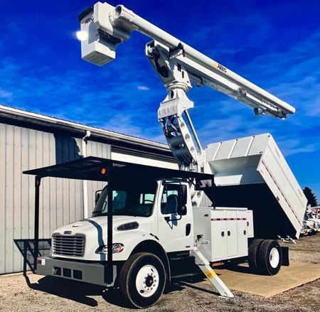 A white truck with a crane on top of it is parked in front of a building.