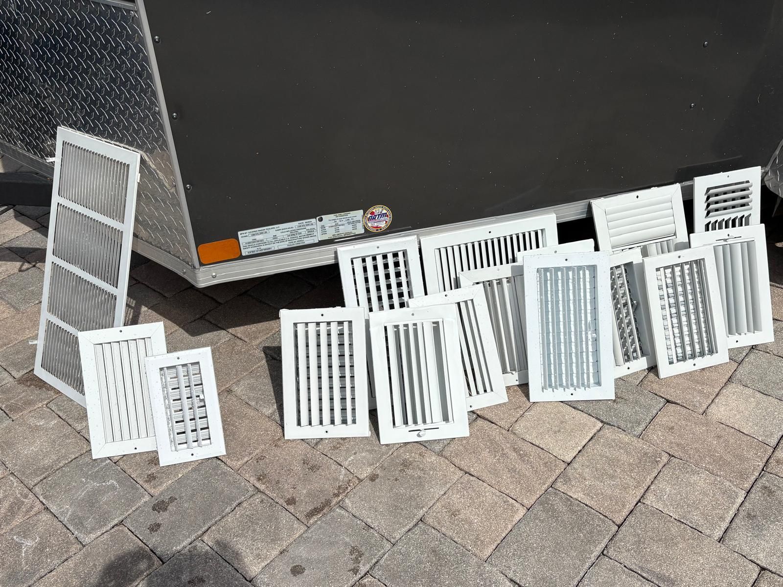 Various white air vent covers and filters arranged on a brick surface.