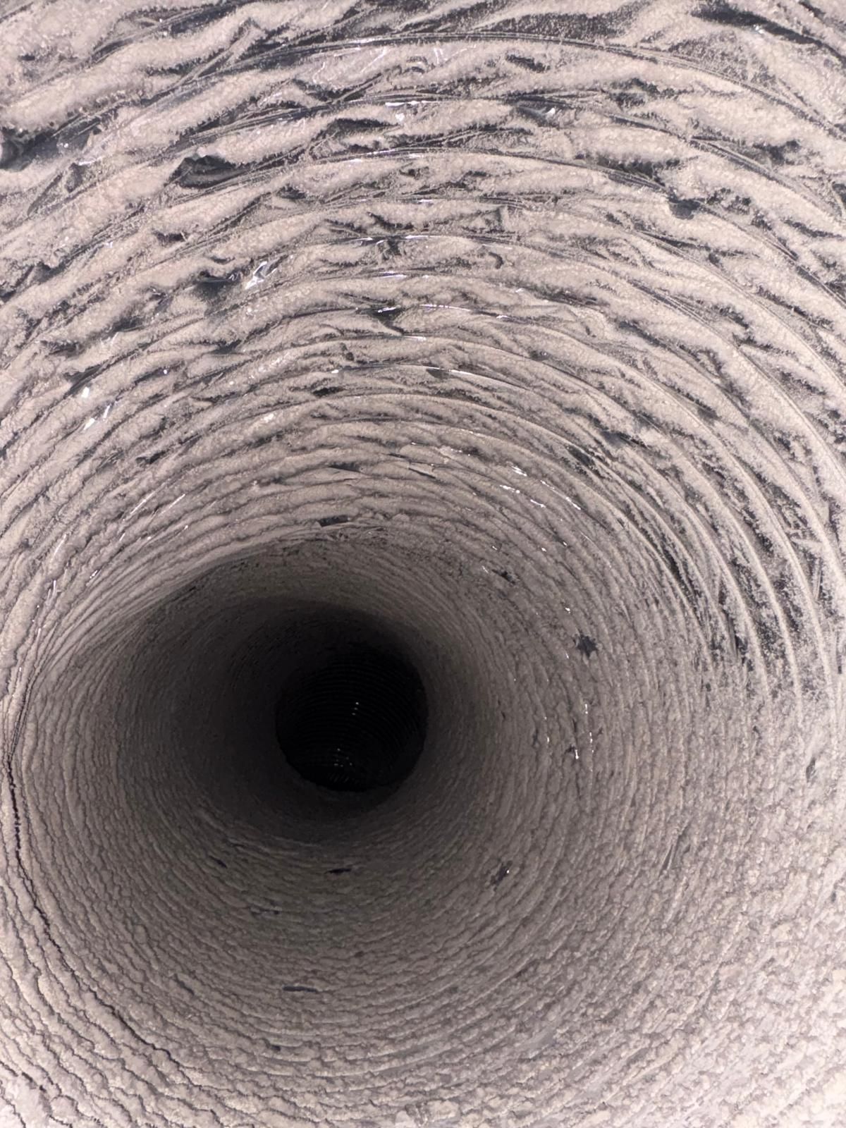 Looking down a dusty, cylindrical vent, dark at the bottom.