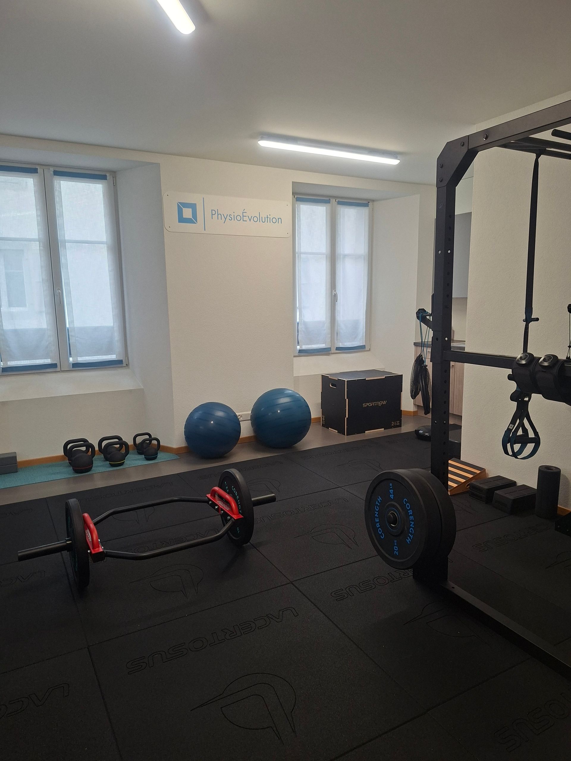 Une salle de sport avec une barre, des fitballs et d'autres équipements d'exercice.