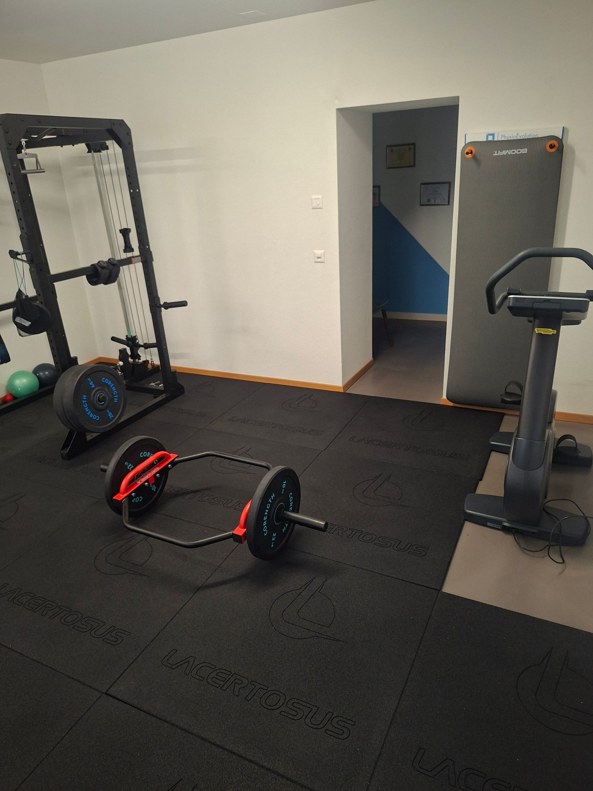 Une salle de sport avec une barre et un tapis roulant au sol