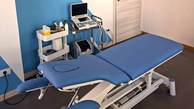Une table de massage bleue avec un ordinateur portable dessus dans une pièce.