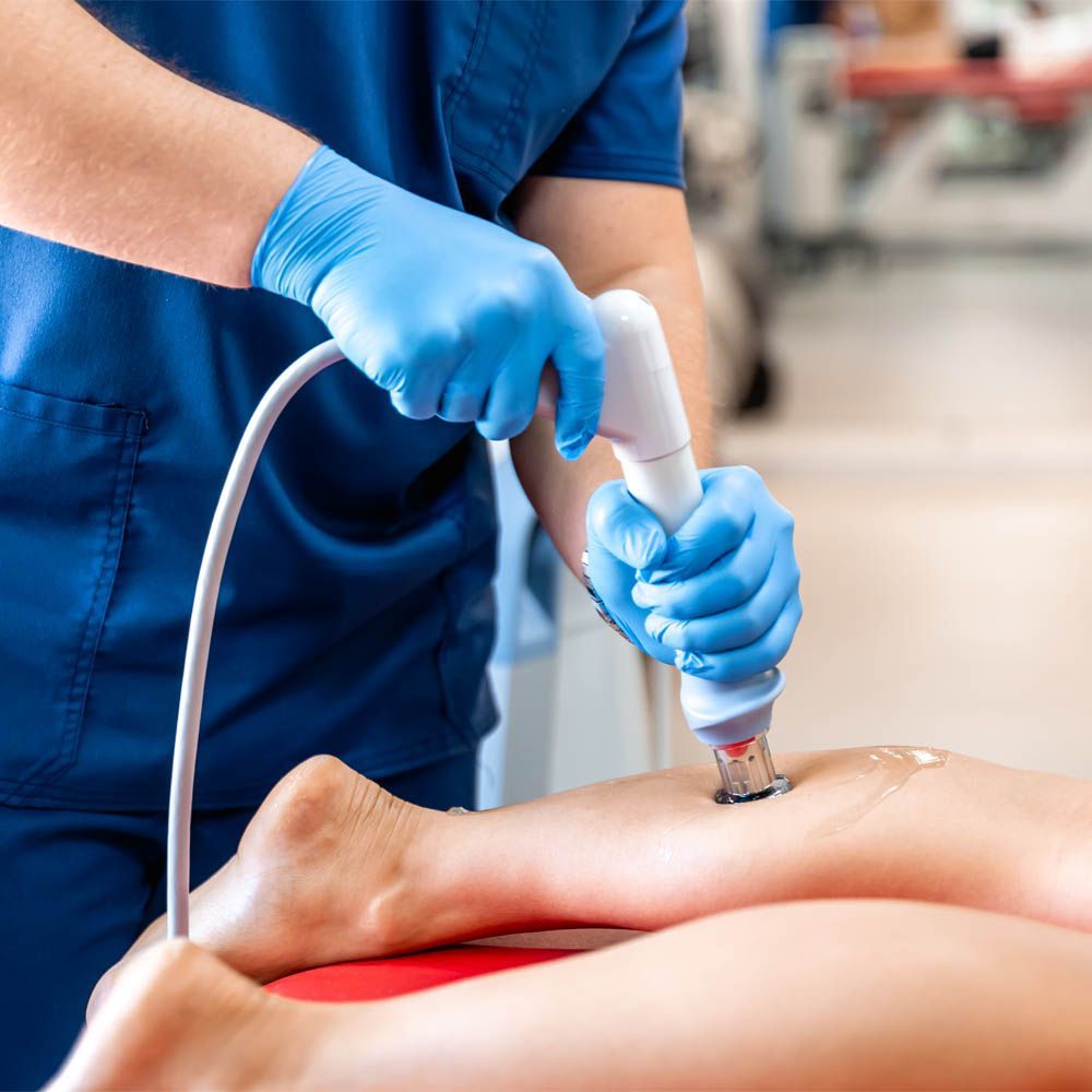 Une infirmière utilise une machine sur la jambe d'un patient.