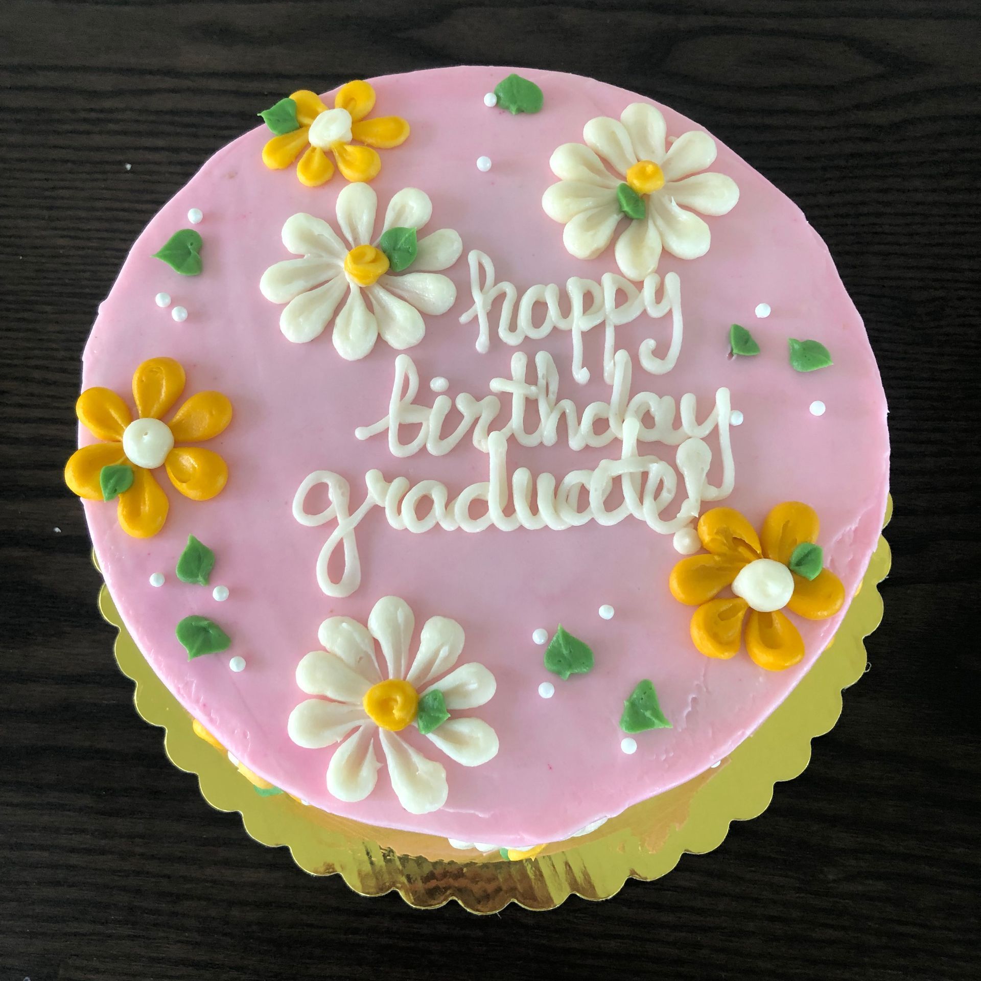 A pink cake that says happy birthday graduate on it