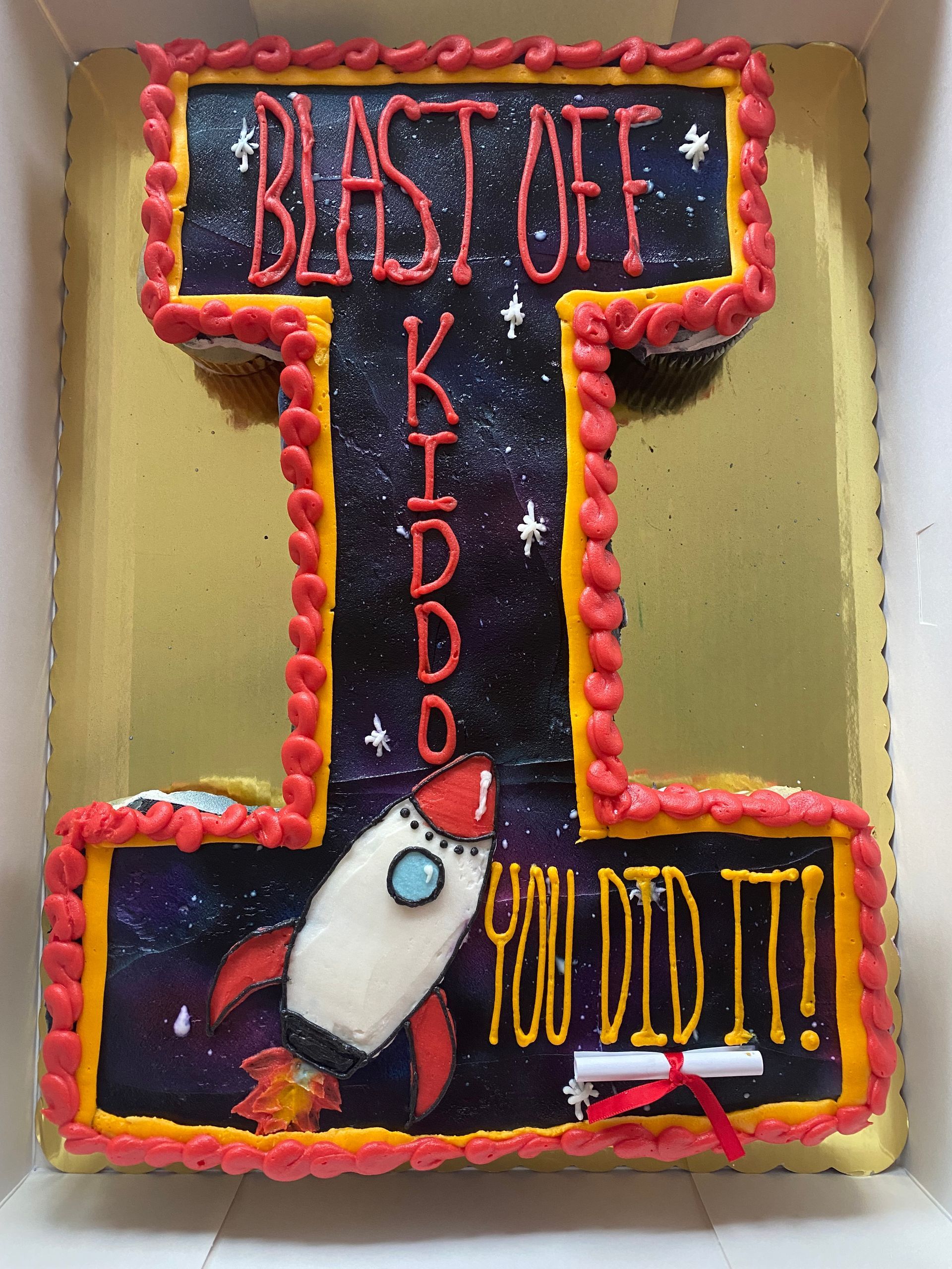 A cake in the shape of an I for ISU that says blast off kiddo you did it