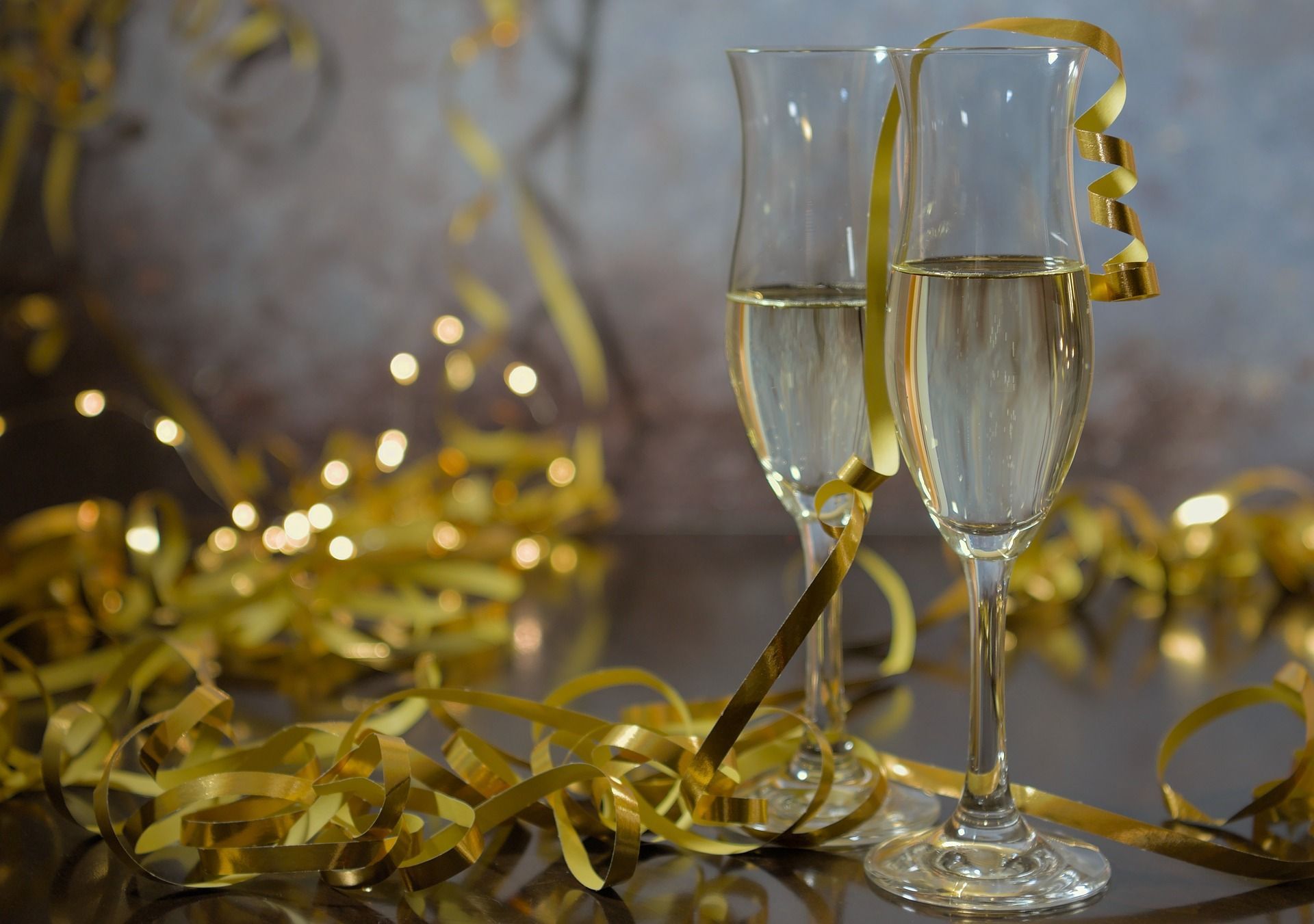 Two glasses of champagne are sitting on a table with gold streamers. New year's resolution