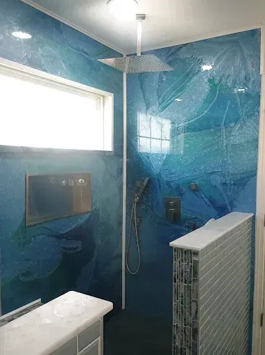 Blue tiled shower with rain showerhead, window, and small built-in shelf.