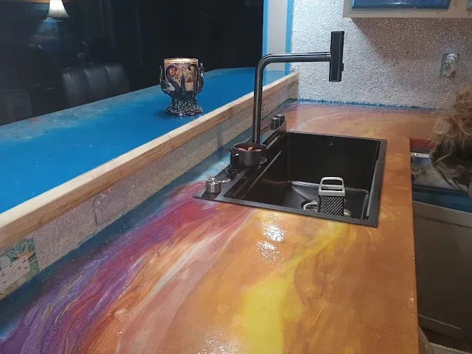 Colorful metallic epoxy countertop with sink and faucet. Bar area with blue accent.