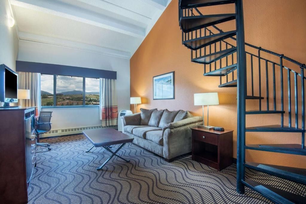 A hotel room with a spiral staircase and a couch.