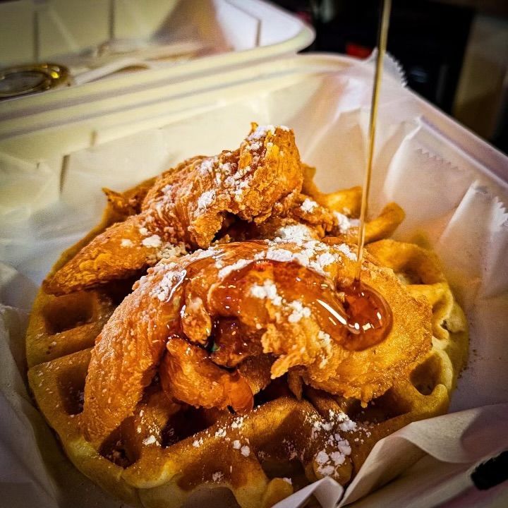 A waffle with fried chicken and syrup on top