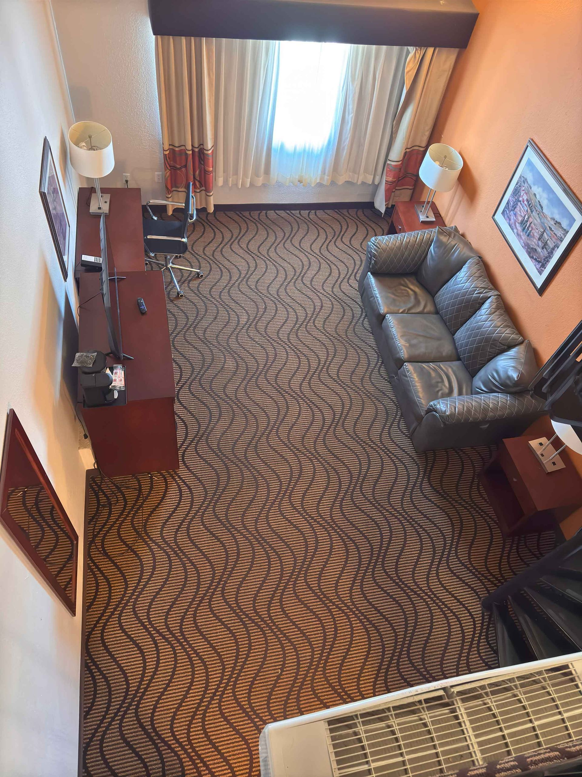 An aerial view of a hotel room with a couch and a desk.