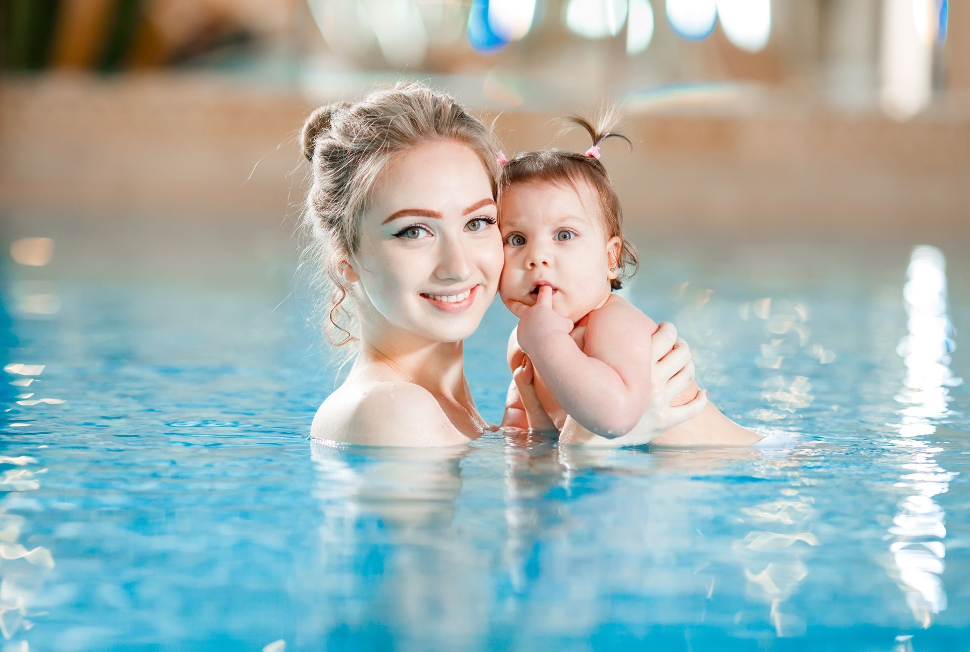 A woman is teaching a baby how to swim in a swimming pool.