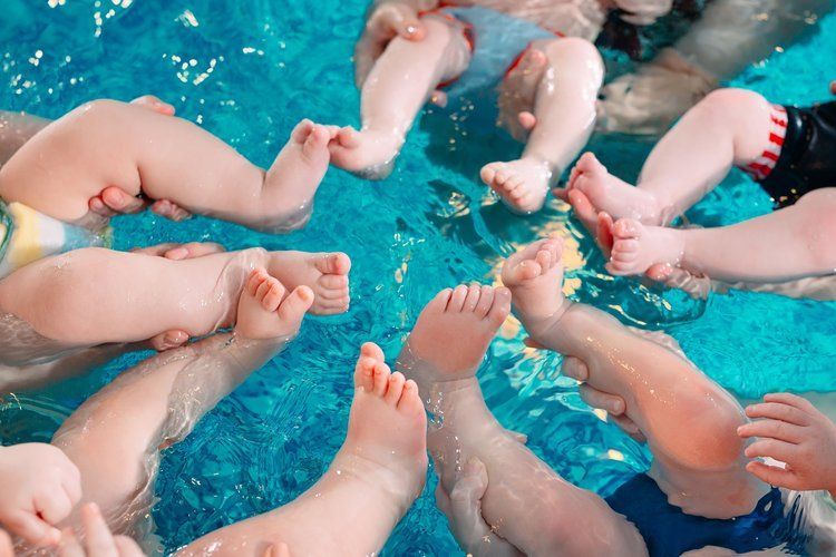 A woman is holding a baby in a swimming pool.