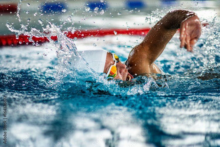 A man is swimming freestyle in a swimming pool.