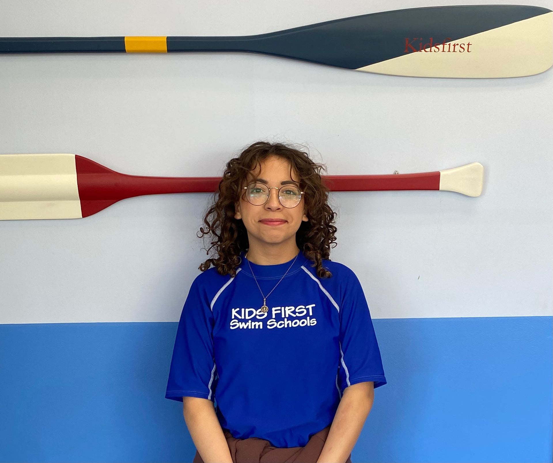 A woman wearing a blue shirt that says kids first swim schools