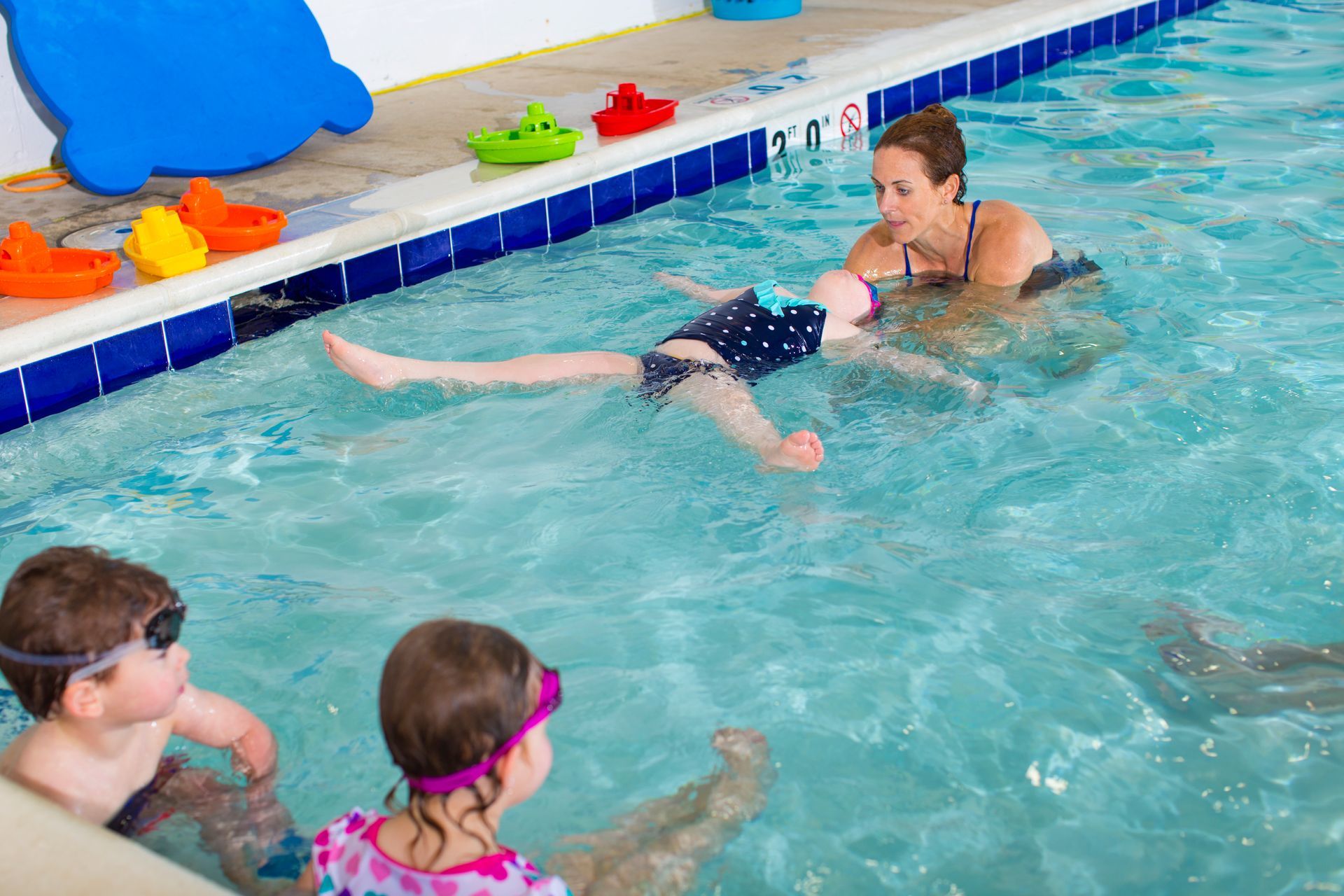 A woman is teaching a child how to swim in a swimming pool.