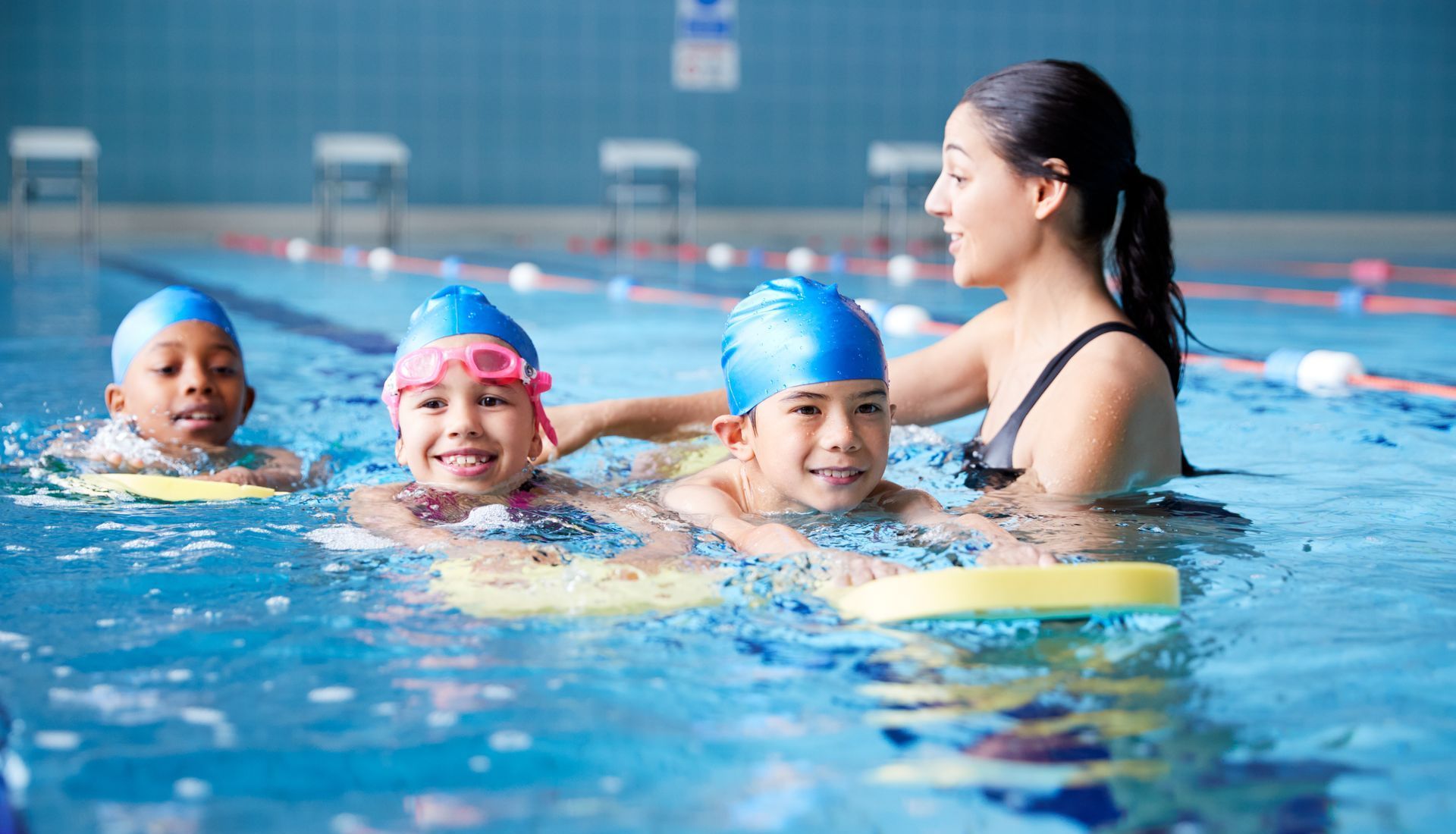 A woman is teaching a group of children how to swim in a swimming pool.