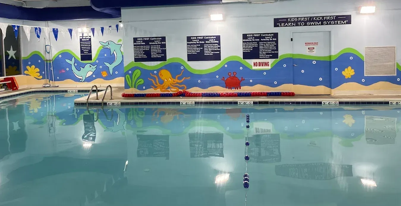 A man is teaching a little boy how to swim in a swimming pool.