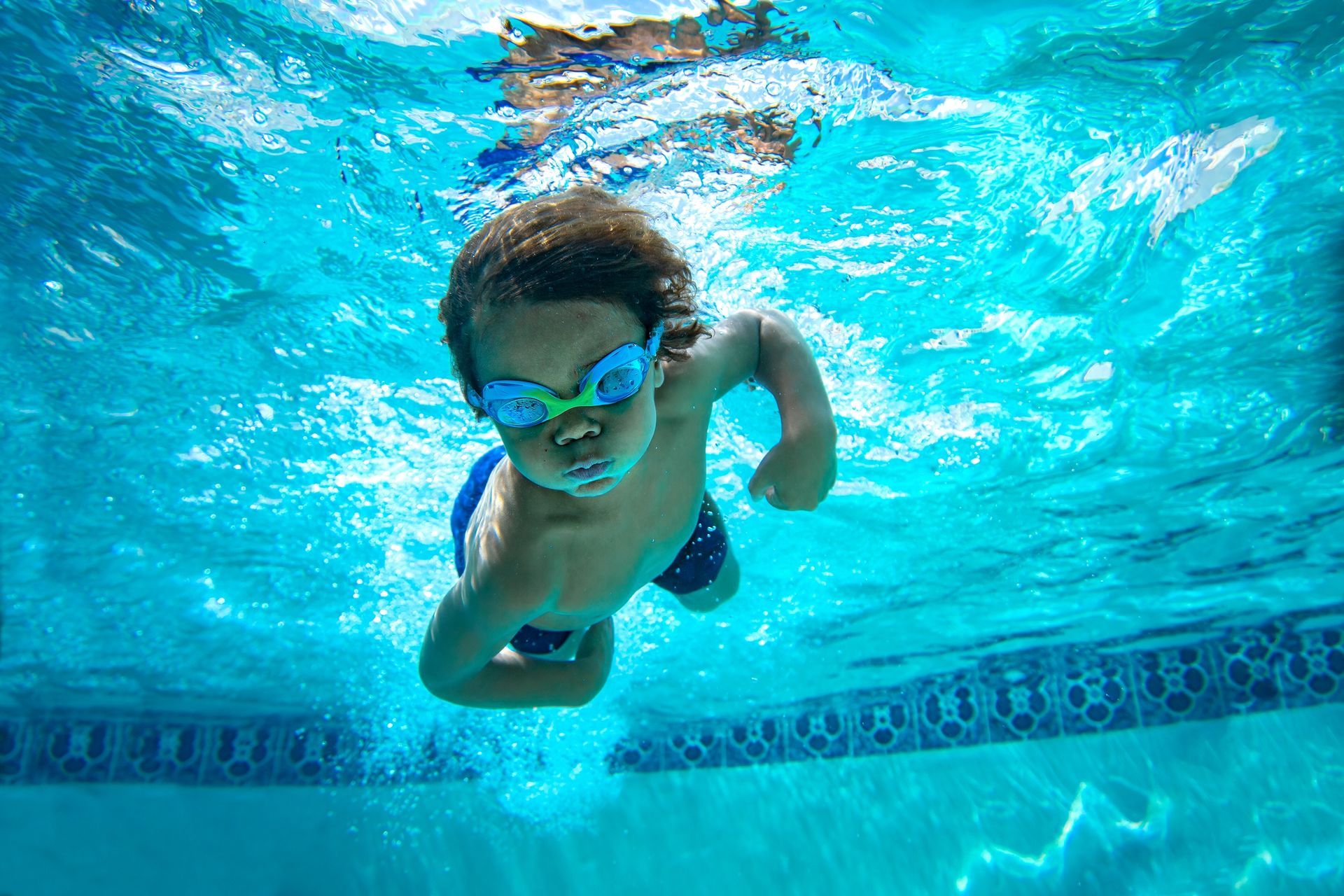 A young boy is swimming underwater in a swimming pool.