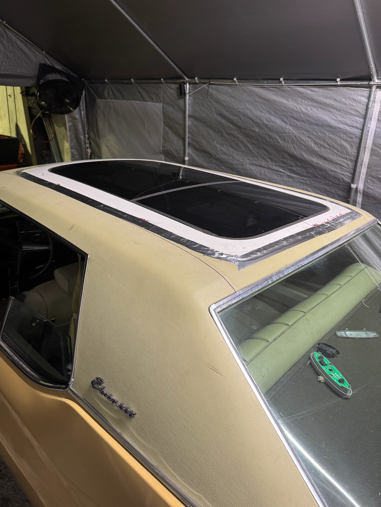 A car with a sunroof is sitting under a tent.