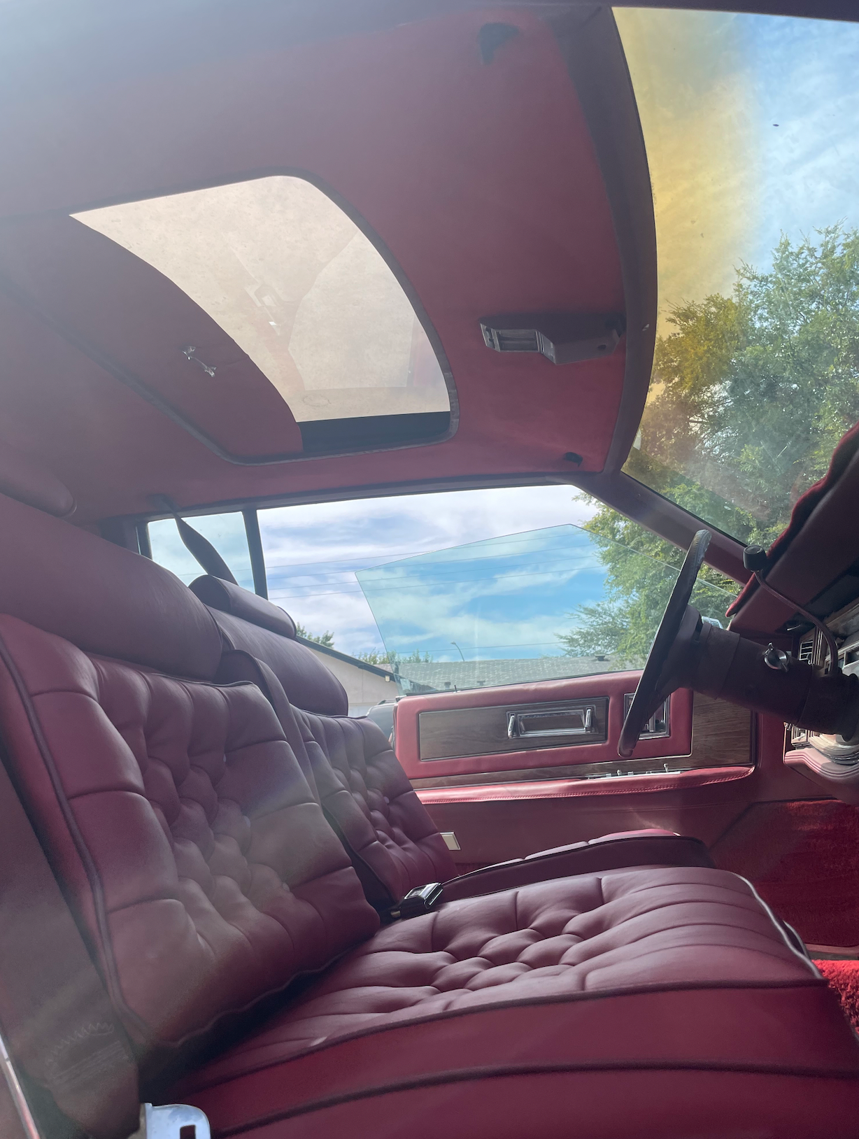 The inside of a car with red seats and a sunroof.