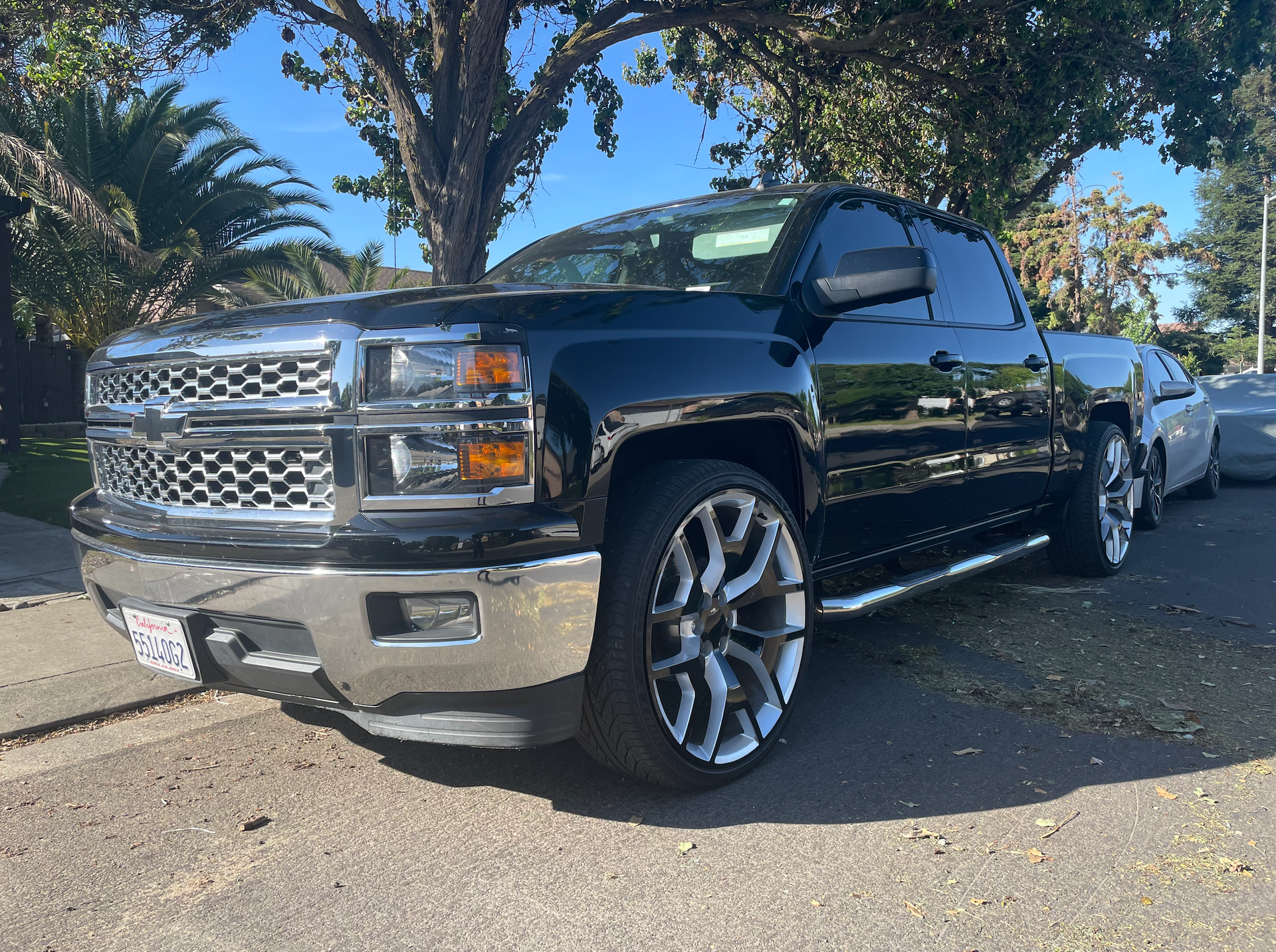 A black chevrolet silverado truck is parked on the side of the road.