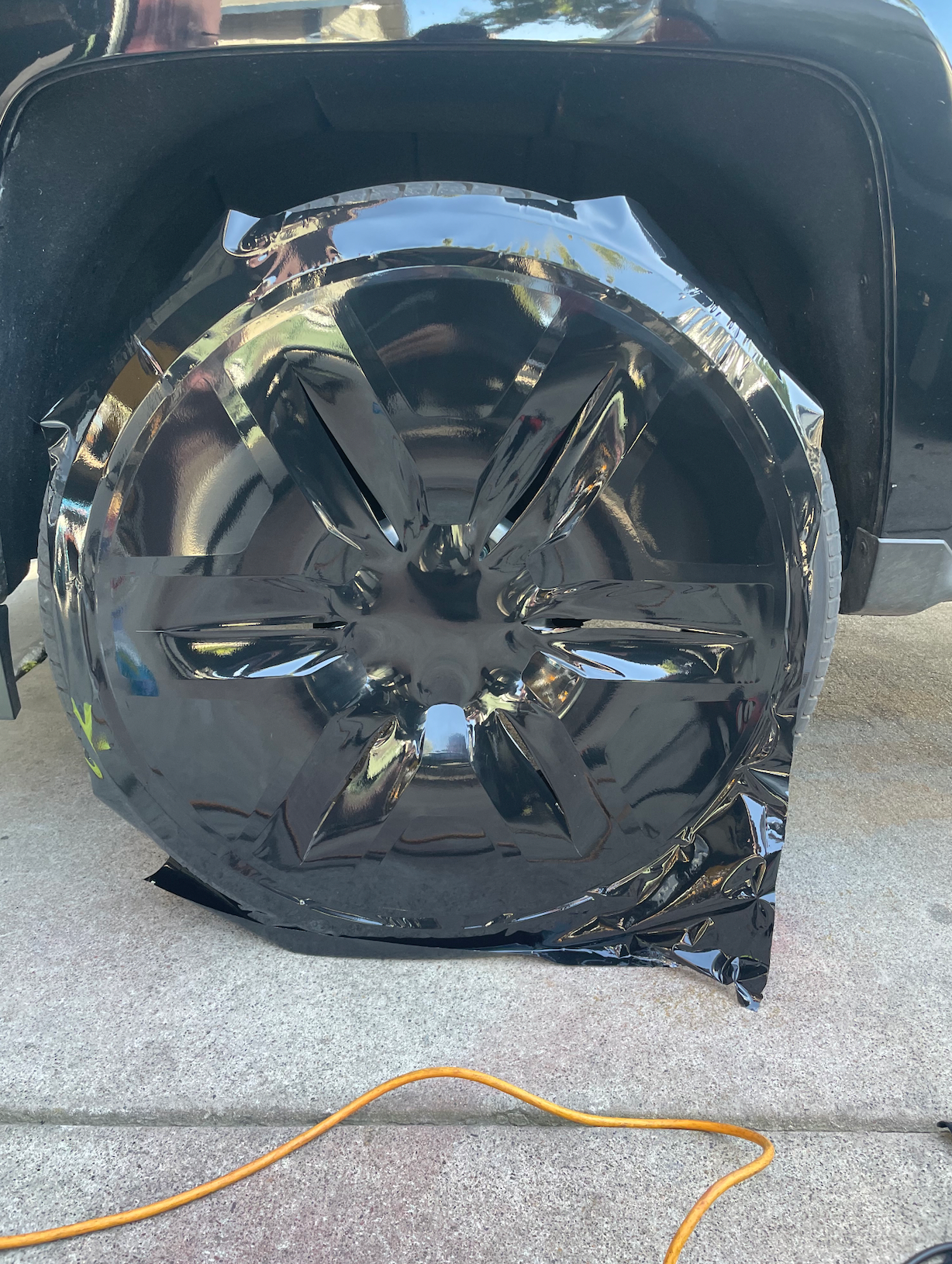 A black tire is wrapped in black tape on the side of a car.