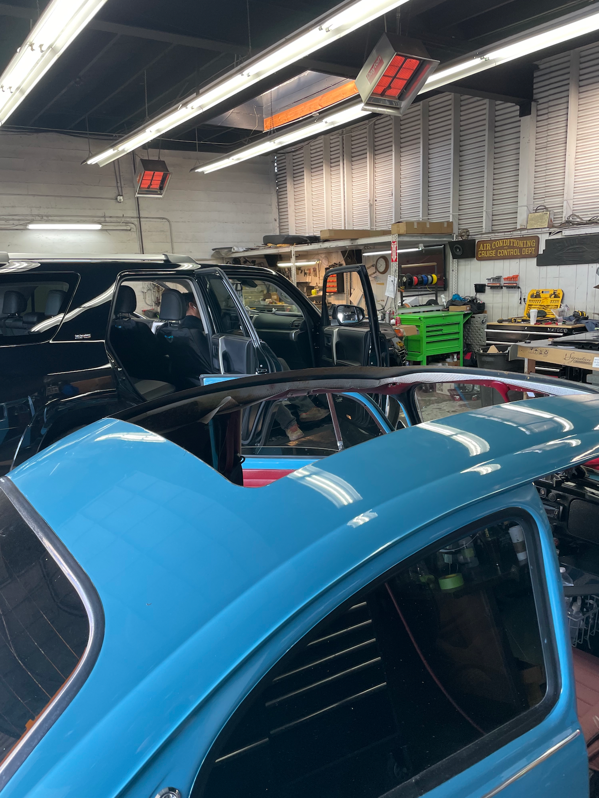A blue car is being worked on in a garage.
