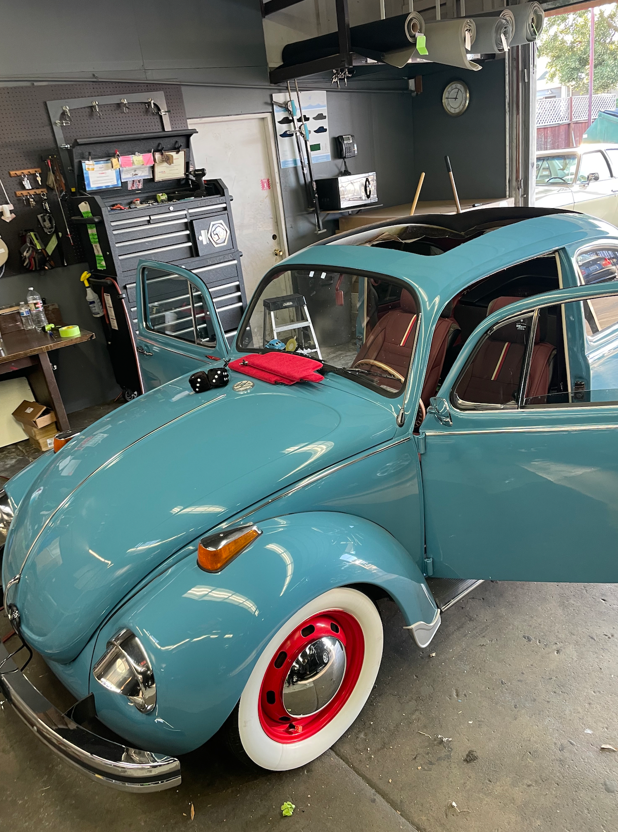 A blue beetle is parked in a garage with its doors open.