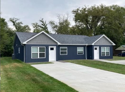 A blue and gray house with a concrete driveway in front of it.