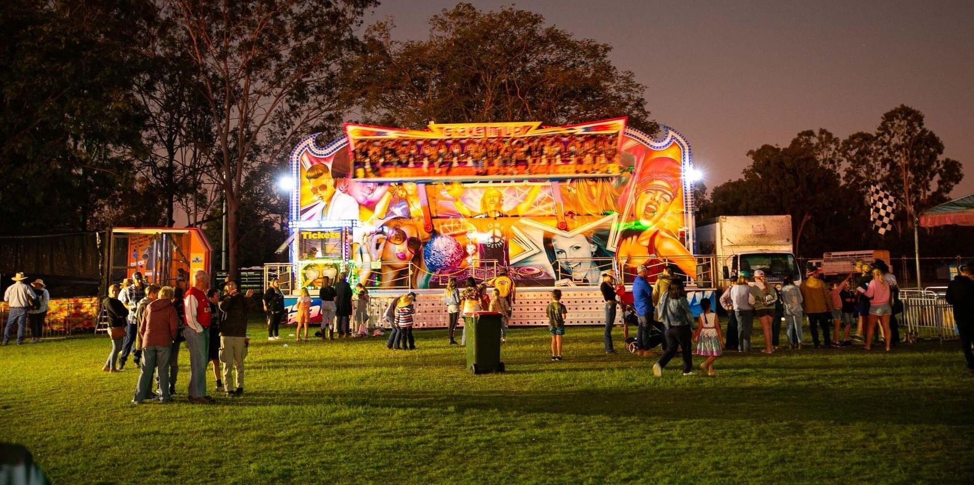 A Brightly Lit Carnival Ride at Night, With People on the Lawn and in Front — Fun Time Amusements in Gracemere, QLD