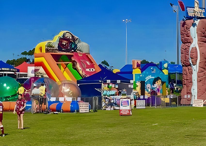 A Group of Children Are Playing in a Field With a Bouncy House — Fun Time Amusements in Gracemere, QLD