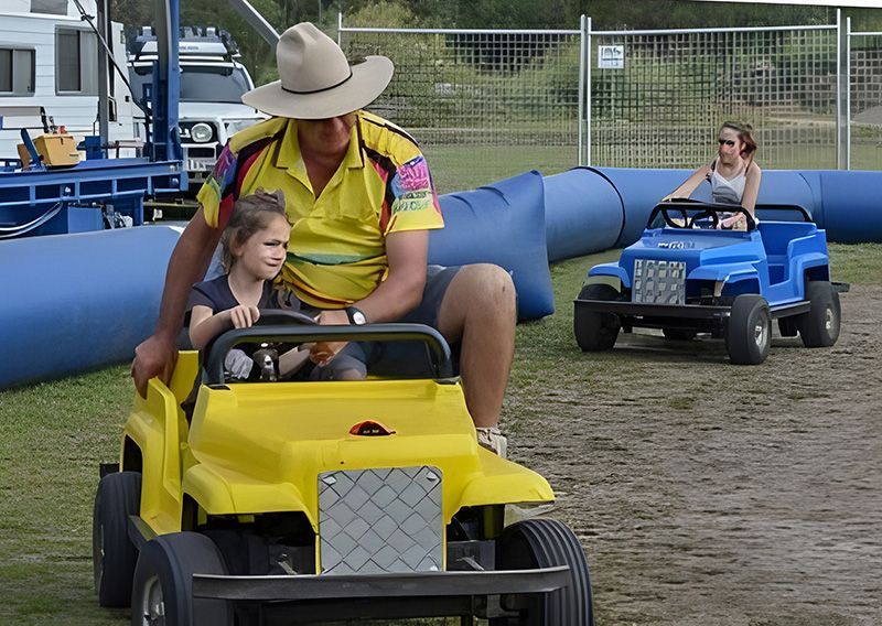 A Man and a Little Girl Are Riding a Yellow Lawn Mower — Fun Time Amusements in Gracemere, QLD