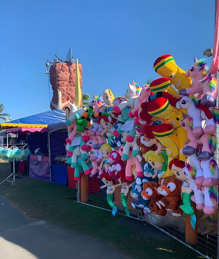 A Bunch of Stuffed Animals Are Hanging on a Fence at a Carnival — Fun Time Amusements in Gracemere, QLD