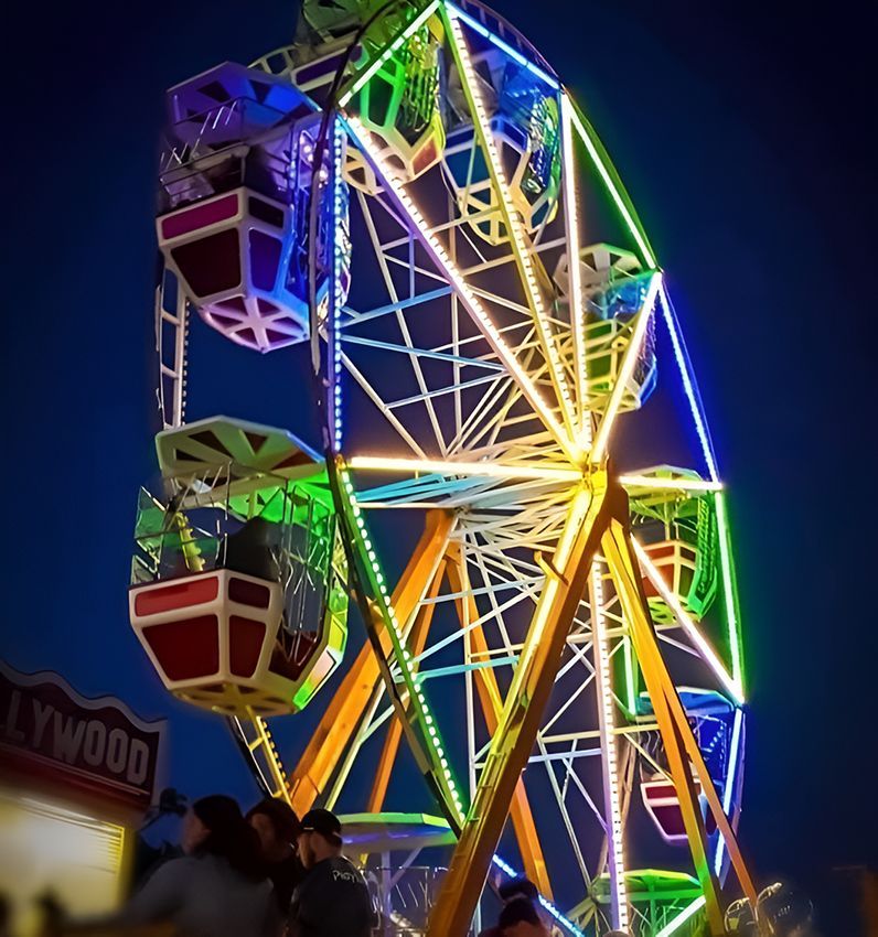 A Ferris Wheel is Lit Up at Night in Front of a Hollywood Sign — Fun Time Amusements in Emerald, QLD