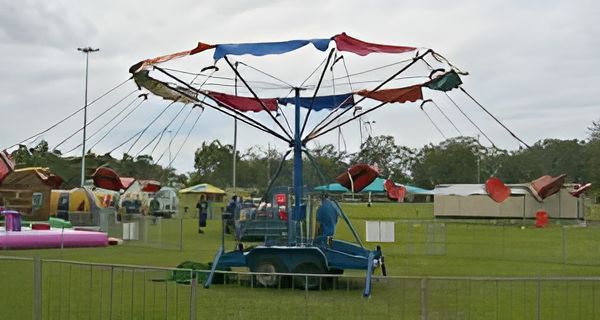 A Small Carnival Swing Ride With Red, Blue, and White Fabric, Set in a Grassy Field — Fun Time Amusements in Gracemere, QLD