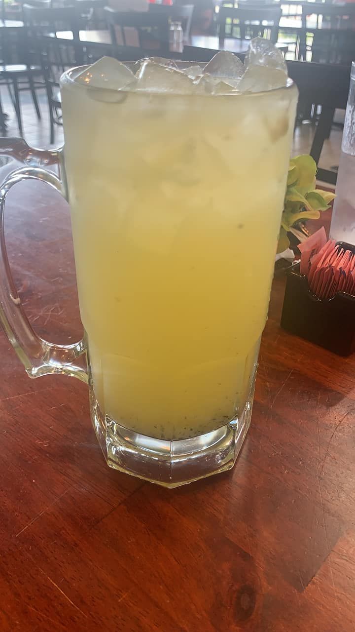 A glass of iced lemonade is sitting on a wooden table.