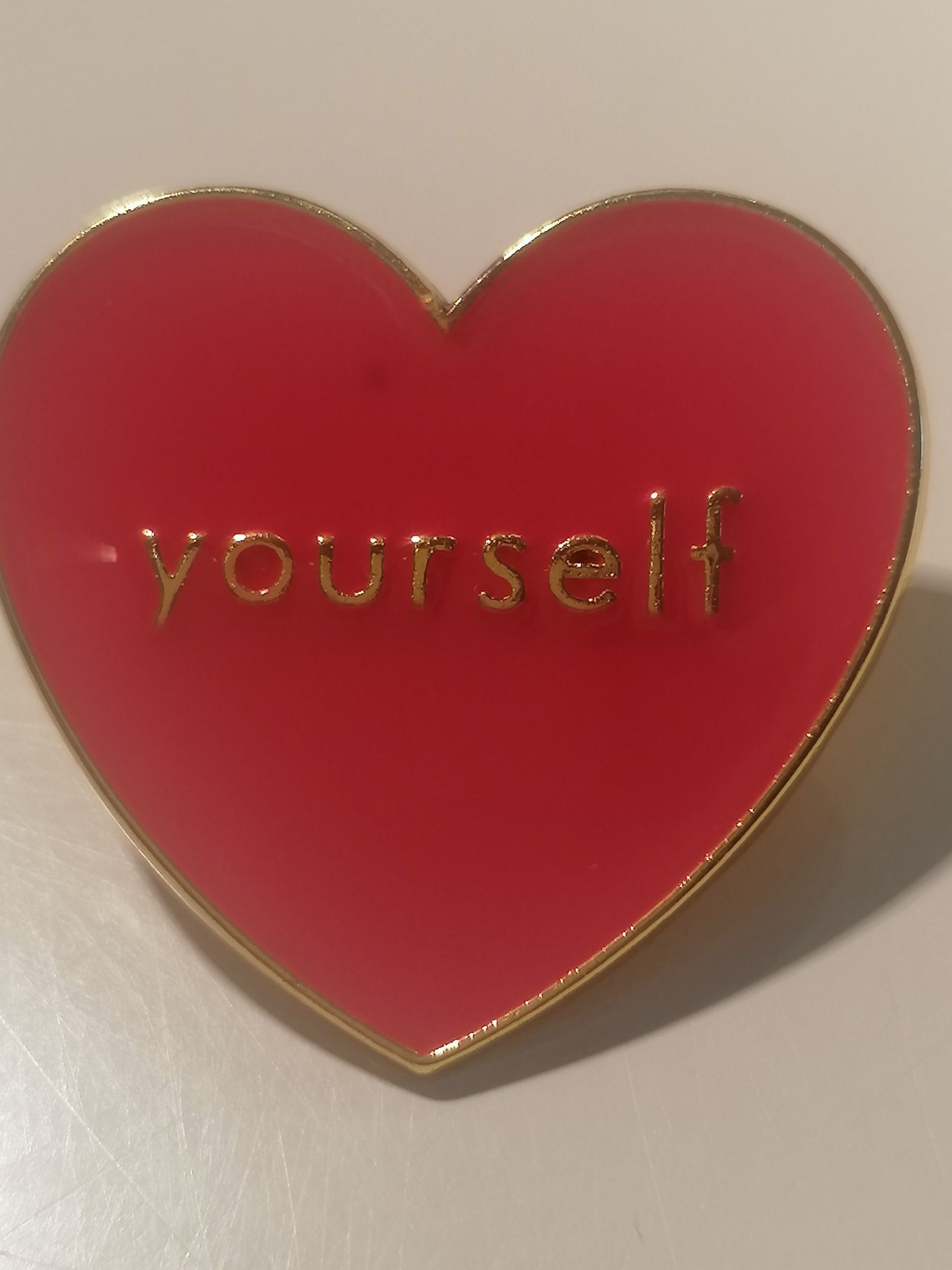 Rode hartvormige speld met gouden rand, het woord