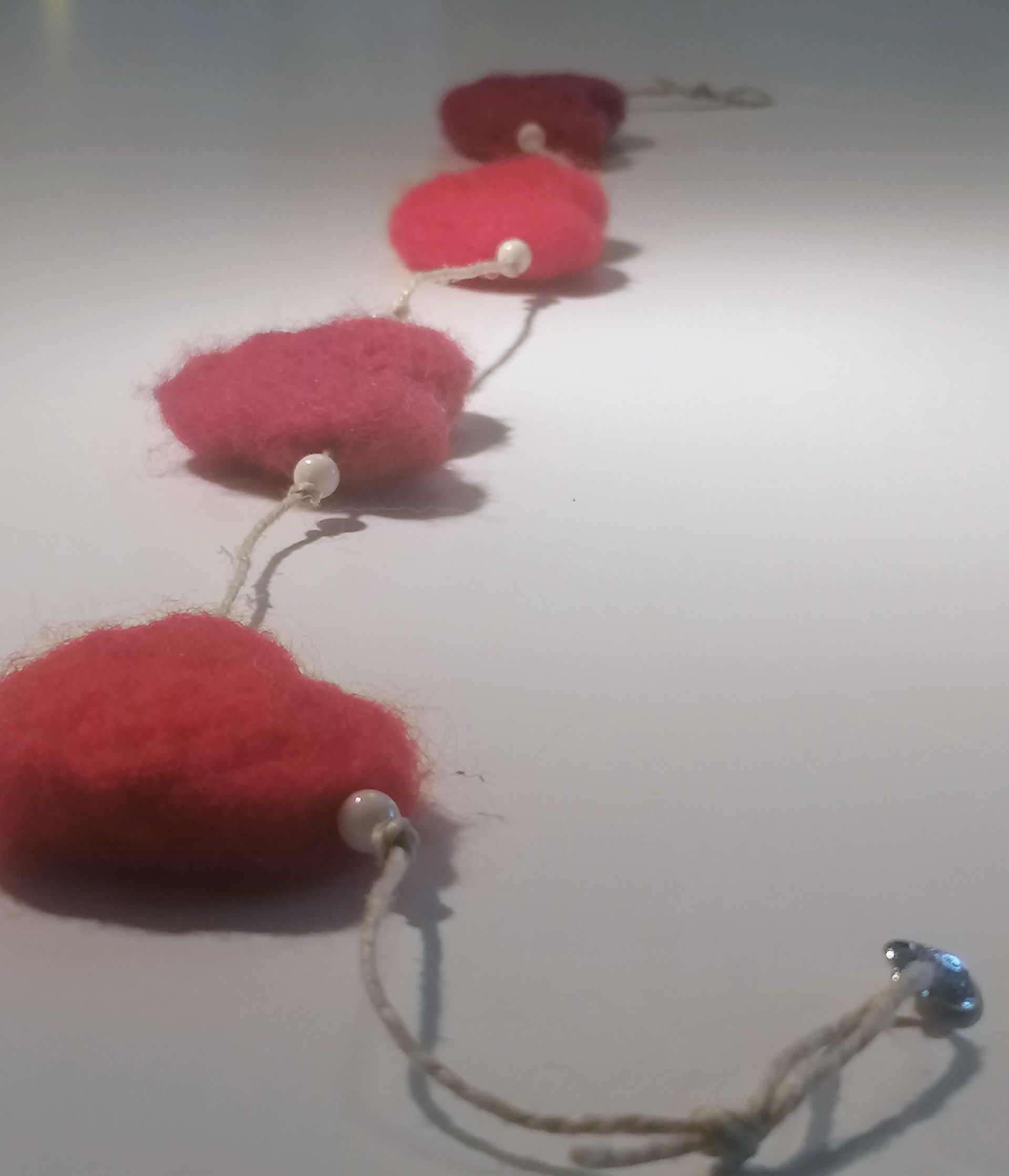 Rode vilten hartenslinger met parelkralen.